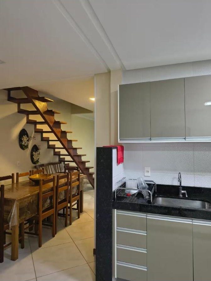 Cozinha integrada à mesa de jantar e à escada para o andar de cima